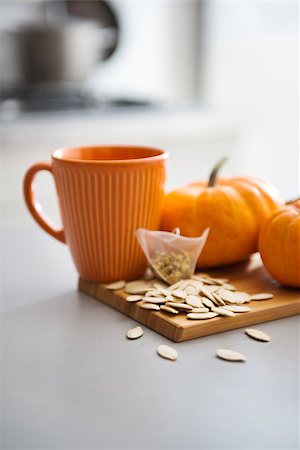 simsearch:400-07956836,k - Closeup of an orange mug sitting on a wooden cutting board featuring pumpkin seeds, tea, and miniature pumpkins. Foto de stock - Royalty-Free Super Valor e Assinatura, Número: 400-08134244