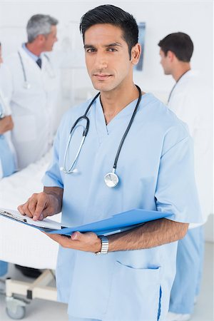 Doctor reading report with colleagues and patient behind Stock Photo - Budget Royalty-Free & Subscription, Code: 400-08136156