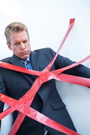 Businessman trapped by red tape on white background Stock Photo - Budget Royalty-Free & Subscription, Code: 400-08136265
