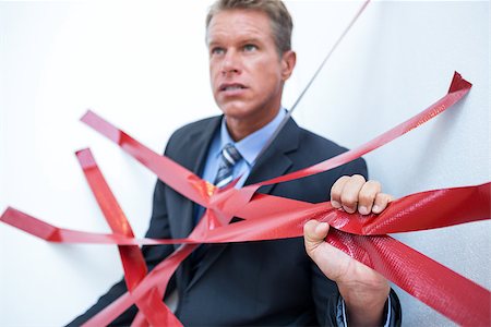 Businessman trapped by red tape on white background Stock Photo - Budget Royalty-Free & Subscription, Code: 400-08136267
