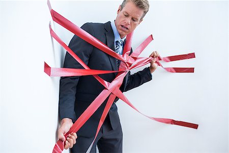 Businessman trapped by red tape on white background Stock Photo - Budget Royalty-Free & Subscription, Code: 400-08136268