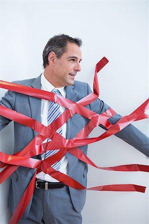 Businessman trapped by red tape on white background Stock Photo - Budget Royalty-Free & Subscription, Code: 400-08136274