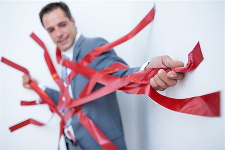 Businessman trapped by red tape on white background Stock Photo - Budget Royalty-Free & Subscription, Code: 400-08136275