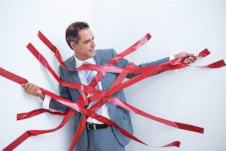 Businessman trapped by red tape on white background Stock Photo - Budget Royalty-Free & Subscription, Code: 400-08136276