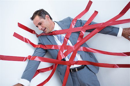 Businessman trapped by red tape on white background Stock Photo - Budget Royalty-Free & Subscription, Code: 400-08136273