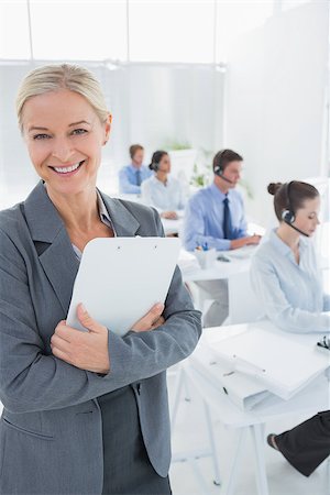 Smiling businesswoman holding a clipboard in call center Stock Photo - Budget Royalty-Free & Subscription, Code: 400-08136444