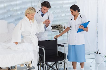 simsearch:6109-06195982,k - Patient trying to sit on wheelchair with help of doctors in hospital Fotografie stock - Microstock e Abbonamento, Codice: 400-08136729