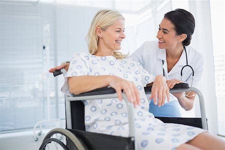 simsearch:6109-06195982,k - Happy doctor smiling at her patient in wheelchair in hospital Fotografie stock - Microstock e Abbonamento, Codice: 400-08136722