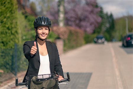 Smiling Active Businesswoman on her Bicycle with Helmet Showing Thumbs up While Looking at the Camera. Stock Photo - Budget Royalty-Free & Subscription, Code: 400-08154034