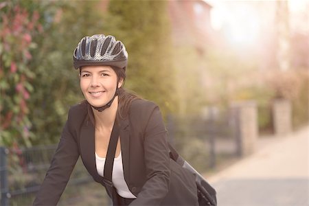 Happy Young Businesswoman Biking at the Street with Head Gear Going to her Office, Looking at the Camera Stock Photo - Budget Royalty-Free & Subscription, Code: 400-08154033