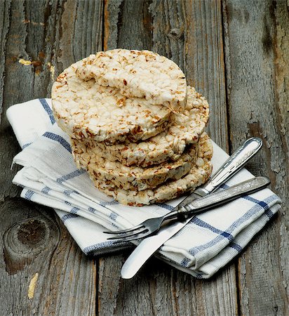 Stack of Puffed Spelt Oat Galettes with Silverware Fork and Knife on Checkered Napkin closeup on Rustic Wooden background. Health Eating Concept Photographie de stock - Aubaine LD & Abonnement, Code: 400-08155632