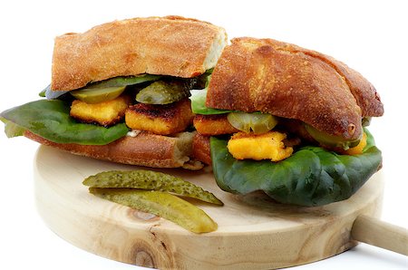 Homemade Fish Burgers with White Fish Sticks, Lettuce, Gherkins and Whole Wheat Bread on Circle Wooden Cutting Board isolated on white background Fotografie stock - Microstock e Abbonamento, Codice: 400-08155921