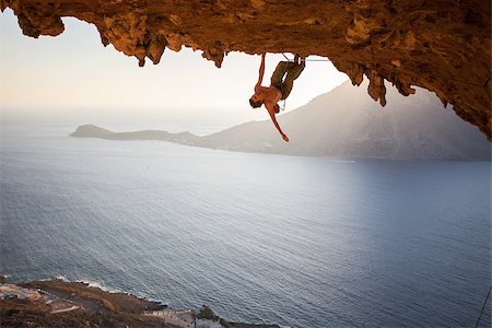 simsearch:400-08072896,k - Male rock climber climbing along a roof in a cave at sunset Foto de stock - Royalty-Free Super Valor e Assinatura, Número: 400-08151303