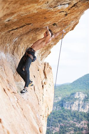 simsearch:400-07292725,k - Young man clipping rope while clinging to cliff under ledge, challenging part of route Photographie de stock - Aubaine LD & Abonnement, Code: 400-08151342