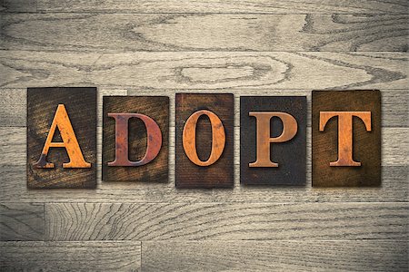 The word "ADOPT" theme written in vintage, ink stained, wooden letterpress type on a wood grained background." theme written in vintage, ink stained, wooden letterpress type on a wood grained background. Stock Photo - Budget Royalty-Free & Subscription, Code: 400-08152377