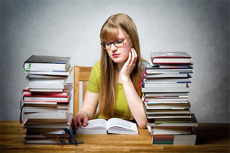 school girl holding pile of books - young woman with lots of books at a table is reading bored book Stock Photo - Budget Royalty-Free & Subscription, Code: 400-08152518
