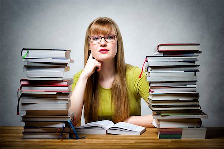 school girl holding pile of books - Young student with glasses sitting at a table with many books Stock Photo - Budget Royalty-Free & Subscription, Code: 400-08152519