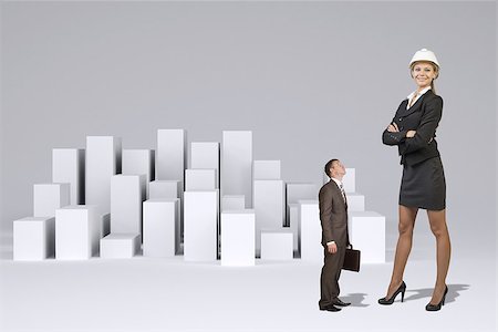 Small businessman in suit with briefcase looking at large businesswoman in suit and helmet. Many white cubes as backdrop Foto de stock - Super Valor sin royalties y Suscripción, Código: 400-08153337