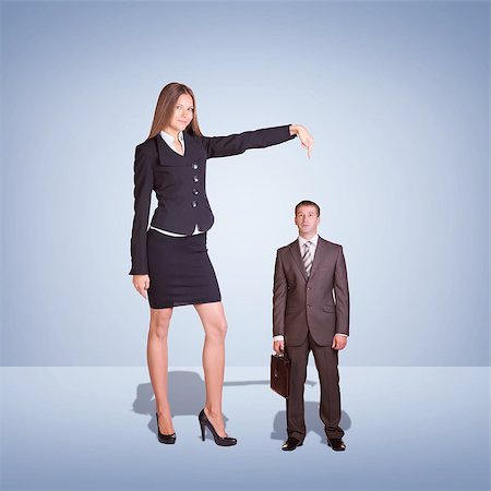 standing tall concept business - Smiling Young Businesswoman Pointing to small Businessman. Blue background Stock Photo - Budget Royalty-Free & Subscription, Code: 400-08153341