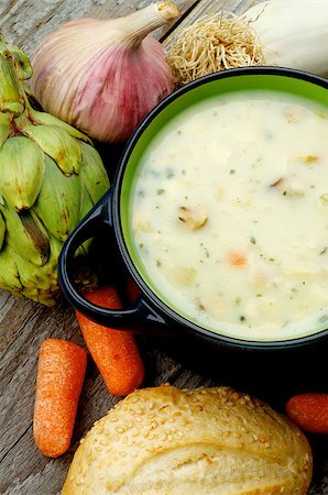 simsearch:400-06485810,k - Healthy Artichoke Creamy Soup with Leek, Carrot, Garlic and Cheese in Dark Blue Pannikin with Sesame Bun closeup on Rustic Wooden background. Top View Fotografie stock - Microstock e Abbonamento, Codice: 400-08153385