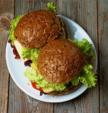 simsearch:400-06330800,k - Homemade Hamburgers with Roasted Beef, Lettuce,Tomato, Onions, Cheese and Bacon with Whole Wheat Bun on White Plate on Rustic Wooden background. Top View Stock Photo - Budget Royalty-Free & Subscription, Code: 400-08160657
