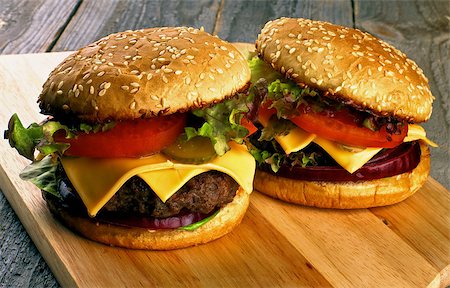 simsearch:600-04625543,k - Homemade Hamburgers with Beef, Tomato, Lettuce, Pickle, Red Onion and Cheese into Sesame Buns closeup on Wooden Cutting Board Stock Photo - Budget Royalty-Free & Subscription, Code: 400-08161943