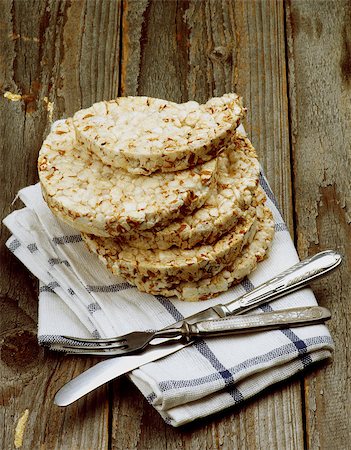 Health Eating Concept with Stack of Puffed Spelt Oat Galettes, Silverware Fork and Knife on Checkered Napkin closeup on Rustic Wooden background Photographie de stock - Aubaine LD & Abonnement, Code: 400-08161950