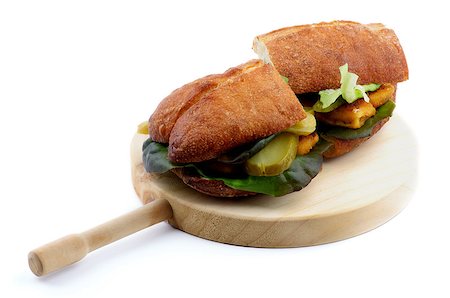 Delicious Fish Burgers with White Fish Sticks, Lettuce, Gherkins and Whole Wheat Bread on Circle Wooden Cutting Board isolated on white background Fotografie stock - Microstock e Abbonamento, Codice: 400-08161952