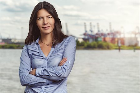 Half Body Shot of a Confident Pretty Young Woman Smiling at the Camera with Arms Crossing In Front her Body Against Hazy River Background. Stock Photo - Budget Royalty-Free & Subscription, Code: 400-08163135