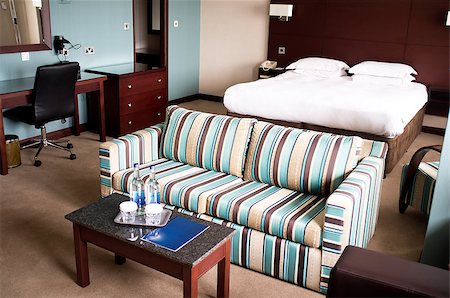 Suite room of a hotel with a sofa neatly placed in the middle and mini table placed Stock Photo - Budget Royalty-Free & Subscription, Code: 400-08185178