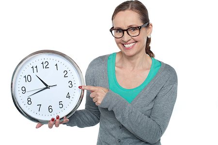 Pretty woman pointing at the wall clock she is holding in other hand. Stock Photo - Budget Royalty-Free & Subscription, Code: 400-08185402