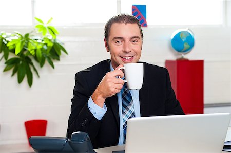 Boss at his workstation posing with coffee mug and laptop open in front of him. Stock Photo - Budget Royalty-Free & Subscription, Code: 400-08185751