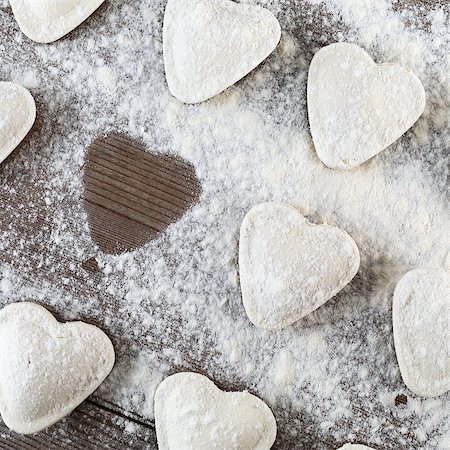 Cooking ravioli.  Raw dumplings in the shape of hearts, sprinkle with flour, on dark wooden table. Top view. Stock Photo - Budget Royalty-Free & Subscription, Code: 400-08188611