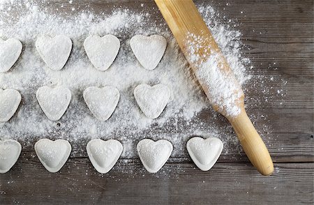 Cooking dumplings. Raw heart shaped dumplings, flour and rolling pin on wooden background. Top view. Stock Photo - Budget Royalty-Free & Subscription, Code: 400-08188612