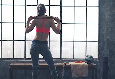 simsearch:400-08189778,k - A fit, strong, muscular woman stands holding a towel across her shoulders while looking out of the window in a city loft gym. Foto de stock - Super Valor sin royalties y Suscripción, Código: 400-08189759