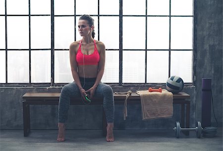 simsearch:400-08189778,k - Looking off to the side, a fit woman in workout gear is sitting on a bench, listening to music. Perhaps she is waiting for her favorite yoga class to begin... Foto de stock - Super Valor sin royalties y Suscripción, Código: 400-08189777