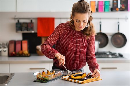 simsearch:400-07956018,k - Finally ready... An elegant woman standing in a kitchen serves a slice of roasted pumpkin onto a plate to serve to her Thanksgiving guests. Stockbilder - Microstock & Abonnement, Bildnummer: 400-08196818