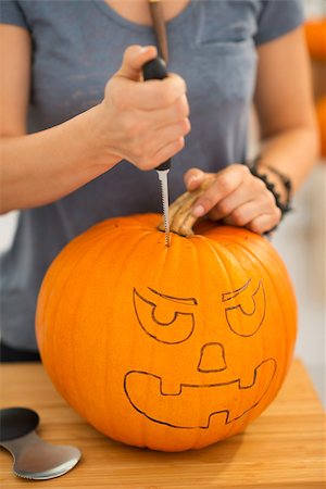 simsearch:400-07172678,k - Close up on woman carving a pumpkin Jack-O-Lantern for Halloween party in kitchen. Traditional autumn holiday Photographie de stock - Aubaine LD & Abonnement, Code: 400-08199658