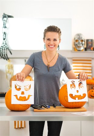 simsearch:400-07172678,k - Happy modern woman holding Halloween carving patterns for making pumpkin Jack-O-Lantern on party in kitchen. Traditional autumn holiday Photographie de stock - Aubaine LD & Abonnement, Code: 400-08199659