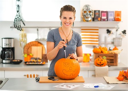 simsearch:400-07172678,k - Smiling young brunette woman carving a big orange pumpkin Jack-O-Lantern for Halloween party Photographie de stock - Aubaine LD & Abonnement, Code: 400-08199664