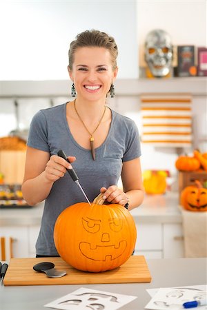 simsearch:400-07172678,k - Cheerful modern woman carving a big orange pumpkin Jack-O-Lantern for Halloween party in kitchen. Traditional autumn holiday Photographie de stock - Aubaine LD & Abonnement, Code: 400-08199661