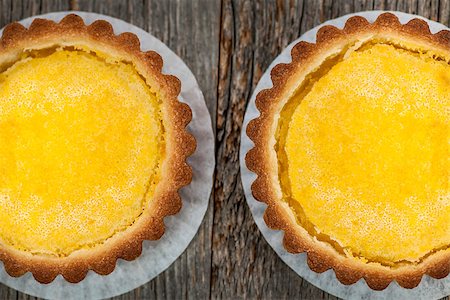 simsearch:400-06946823,k - Two fresh gourmet lemon dessert tarts on wood background from above Fotografie stock - Microstock e Abbonamento, Codice: 400-08199813