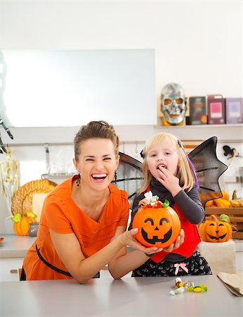 Happy young mother with daughter in bat costume eating colorfull halloween candy in decorated kitchen.  Halloween Candy is so good. Traditional autumn holiday Foto de stock - Super Valor sin royalties y Suscripción, Código: 400-08199926