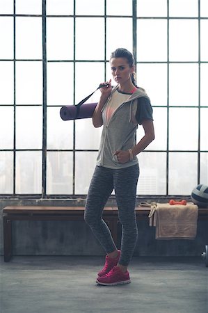simsearch:400-08189778,k - Attitude is what gets you the goal. A healthy, strong, fit woman is looking serious. She is thinking about the workout ahead, casually holding her yoga mat over one shoulder while walking. Foto de stock - Super Valor sin royalties y Suscripción, Código: 400-08193999