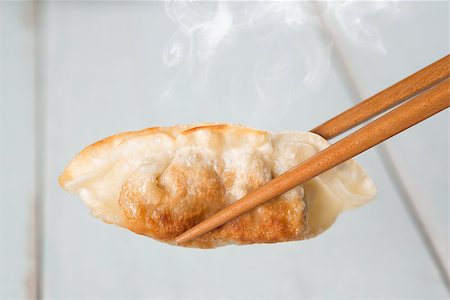 simsearch:400-08225258,k - Close up fresh pan fried dumplings with chopsticks and hot steams. Asian food on rustic vintage wooden background. Foto de stock - Super Valor sin royalties y Suscripción, Código: 400-08224998