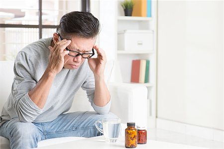 simsearch:400-05251905,k - Portrait of 50s mature Asian man having headache, sitting on sofa at home, indoors living lifestyle. Stock Photo - Budget Royalty-Free & Subscription, Code: 400-08225178