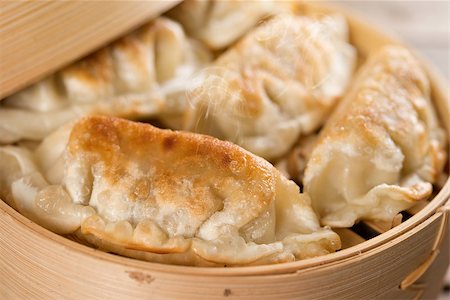 simsearch:400-08225258,k - Close up fresh pan fried dumpling on bamboo basket. Chinese food with hot steams on rustic vintage wooden background. Foto de stock - Super Valor sin royalties y Suscripción, Código: 400-08225256