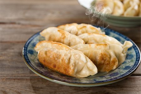 simsearch:400-08225258,k - Fresh pan fried dumpling on plate. Chinese dish with hot steams on rustic vintage wooden background. Fractal on the plate is generic print. Foto de stock - Super Valor sin royalties y Suscripción, Código: 400-08225250