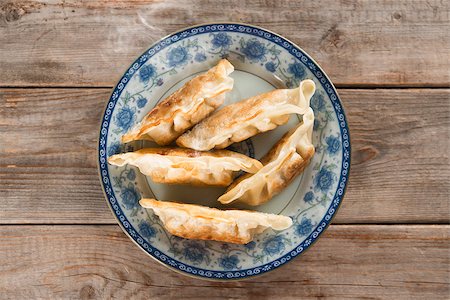 dim sum - Top view fresh pan fried dumpling on plate. Chinese food with hot steams on rustic vintage wooden background. Fractal on the plate is generic print. Foto de stock - Super Valor sin royalties y Suscripción, Código: 400-08225252