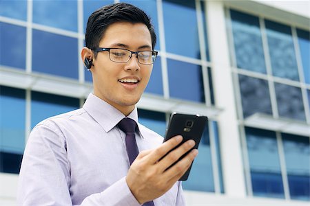 Young chinese businessman doing video conference call on smartphone and talking with bluetooth headset device in the street Stock Photo - Budget Royalty-Free & Subscription, Code: 400-08223020